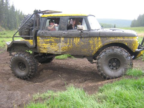 1995 Ford Bronco - This heavily modified truck, covered in mud, navigates a challenging off-road course.
