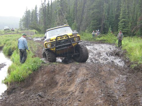 1995 Ford Bronco - A yellow 1979 Ford F-Series truck tackles a challenging muddy course during an off-road event, with other vehicles and spectators in the ba…