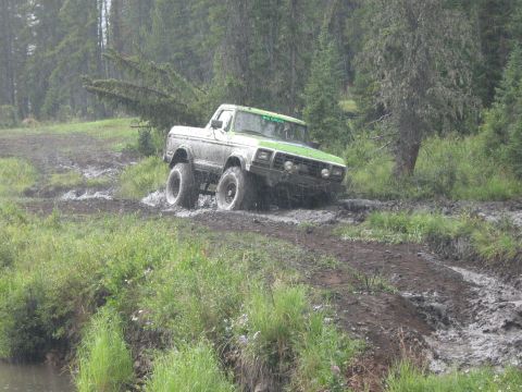 1995 Ford Bronco - A modified Ford truck navigates a muddy off-road trail during a rally.