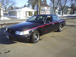 2000 Ford Crown Victoria - A black Ford Crown Victoria with a red stripe is parked on a paved surface.