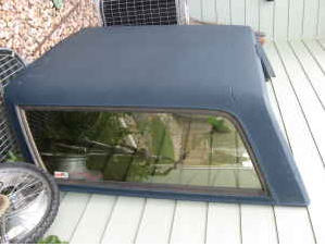 1995 Ford Bronco - A blue truck cap is shown, likely for a Ford Bronco, with a prominent side window and SuperMotors branding at the bottom.
