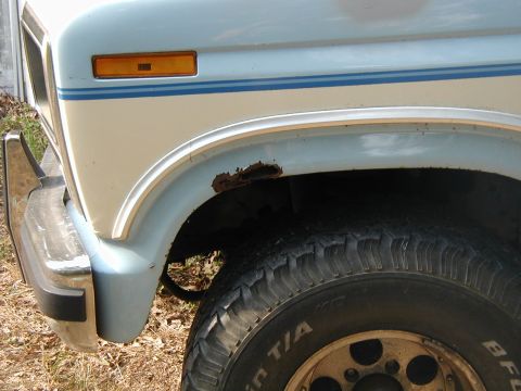 1986 Ford Bronco - Close-up view of the front fender and wheel well of a vehicle, highlighting rust damage.