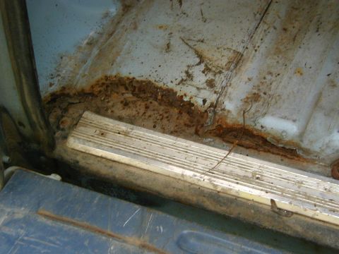 1986 Ford Bronco - Significant rust damage is visible on the interior floor panel and along the trim piece.