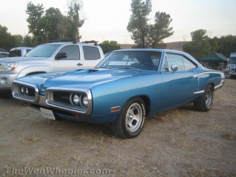 1968 Ford Mustang - A blue 1970 Dodge Super Bee is parked outdoors next to a silver pickup truck.