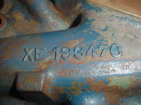 1979 Ford F-150 - A close-up view of a heavily rusted and painted blue engine component displaying stamped identification numbers.