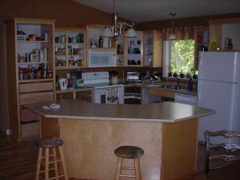 1984 Ford Bronco - A view of a kitchen light wood cabinets, a central island with stools, and a refrigerator.