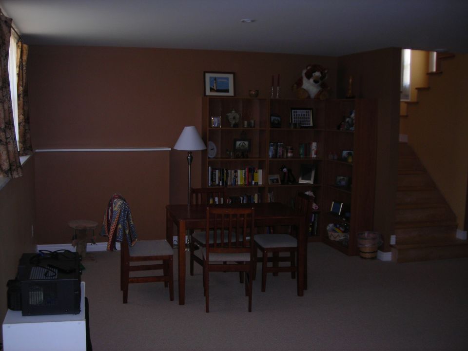 Interior room with dining table, chairs, bookshelves, and stairs