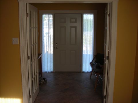 1984 Ford Bronco - This image shows the interior of a home's entryway, a white door flanked by two windows with sheer curtains.