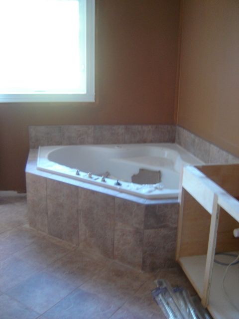 1984 Ford Bronco - Corner jacuzzi tub in a bathroom with tiled surround and a window.