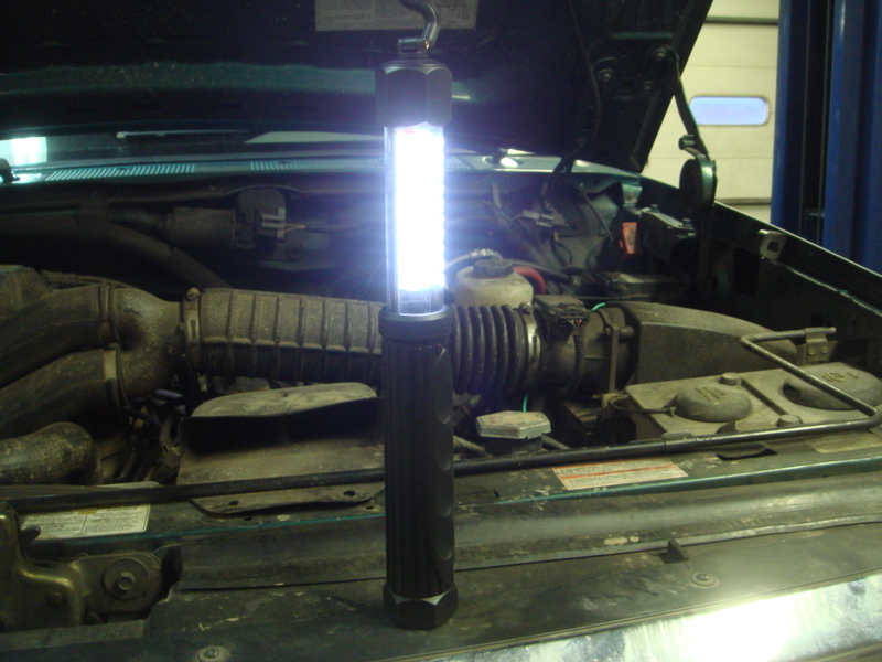 1996 Ford Bronco engine bay with a bright LED work light hanging from the hood