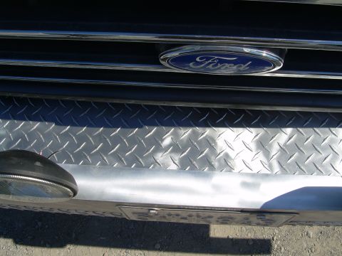 1991 Ford Bronco - Close-up of the front grille and bumper of a 1991 Ford Bronco, the Ford emblem and diamond plate detailing.