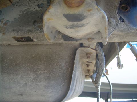 1991 Ford Bronco - Close-up view of a vehicle's undercarriage, revealing mechanical parts and a fuel tank.