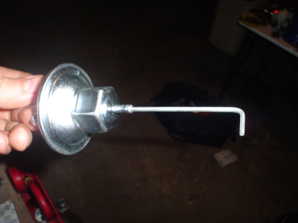 hand holding a metal vacuum advance canister with a rod extending from it