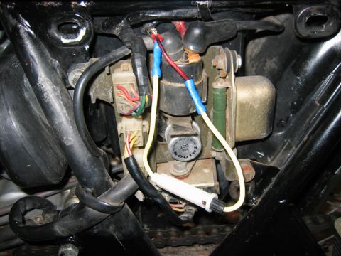 1985 Ford Crown Victoria LTD - Close-up view of motorcycle electrical components, including wiring and a relay, with visible text on a round component.
