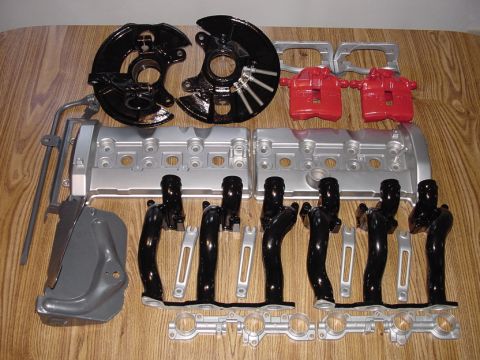 1993 Ford Taurus - Various engine and brake components are arranged on a wooden table, ready for installation or display.