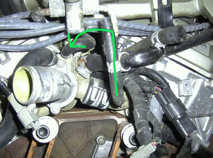 Close-up of engine coolant hose with green arrows indicating flow