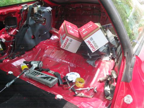 1995 Ford Probe - The interior of a red car is shown with various tools and two boxes of Gabriel Ultra G shocks, suggesting repair or modification work.