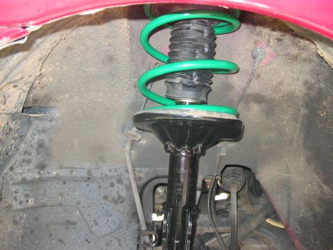 1995 Ford Probe - Front suspension strut assembly with a bright green coil spring.
