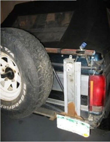 1995 Ford Bronco - The rear of a Ford Bronco is shown with a spare tire and a Hi-Lift jack mounted to the tailgate.