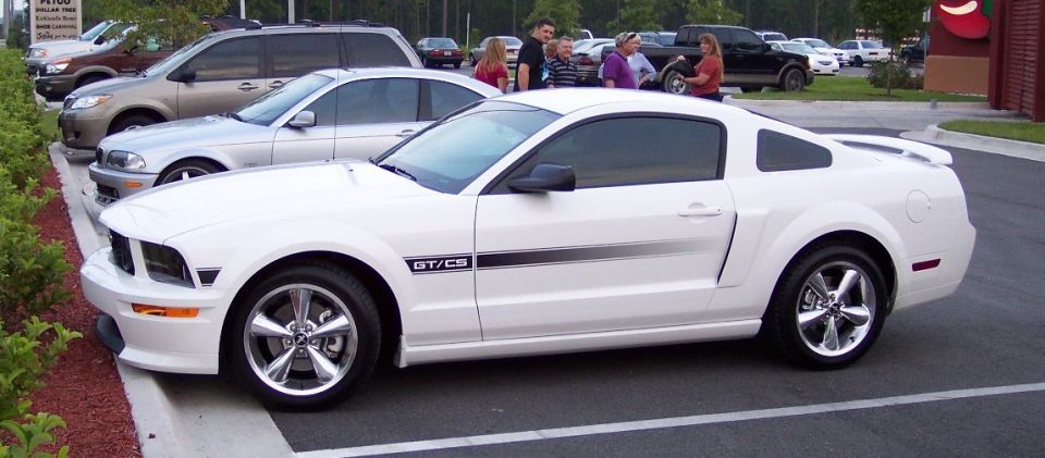 White Ford Mustang GT/CS coupe parked in a lot with people nearby