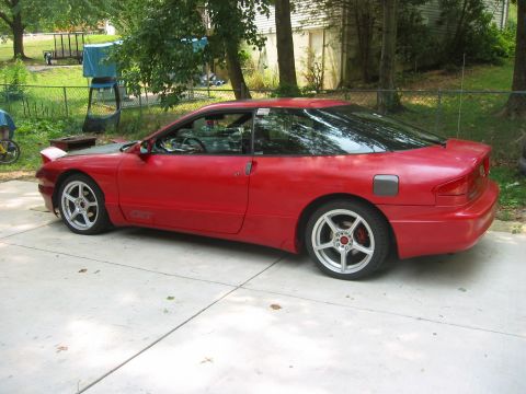 1995 Ford Probe - A red 1995 Ford Probe GT is parked on a concrete driveway in front of a house.