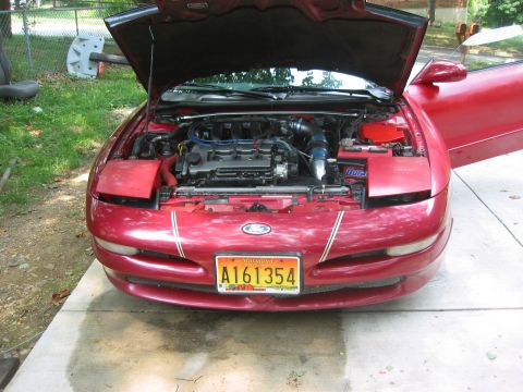 1995 Ford Probe - The front of a red 1995 Ford Probe is shown with its hood and driver's door open, revealing the engine compartment.