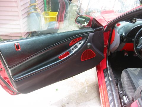 1995 Ford Probe - Interior view of a red car's door panel and dashboard, showing red accents and black upholstery.