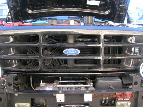 1996 Ford Bronco - Front view of a black Ford truck with the hood open, revealing the grille and a winch mounted below.