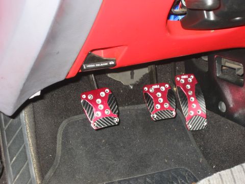 1995 Ford Probe - Aftermarket pedal covers with a red and carbon fiber design are installed on the floor of a vehicle.