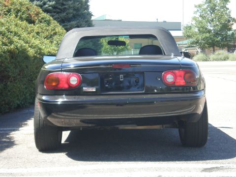 1996 Mazda Miata - Rear view of a black 1996 Mazda Miata convertible, showing its taillights and spoiler.