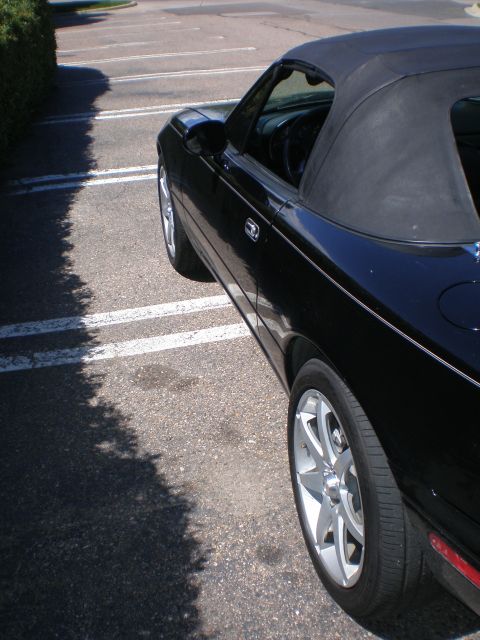 1996 Mazda Miata - Side view of a black 1996 Mazda Miata convertible parked in a lot.