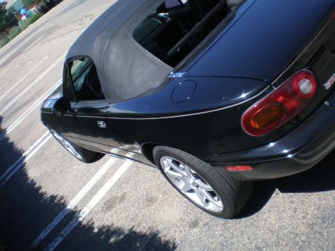 1996 Mazda Miata - A black 1996 Mazda Miata convertible is shown from a high angle, parked in a lot.