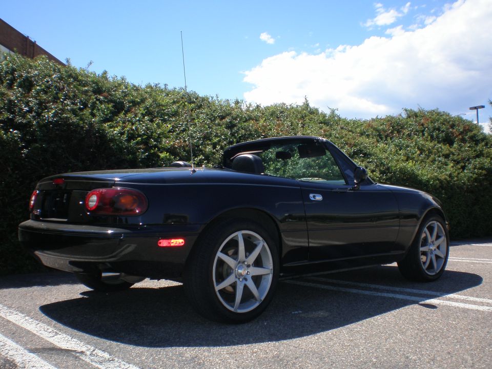 Black convertible sports car with aftermarket wheels parked outdoors