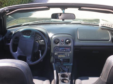 1996 Mazda Miata - The interior of a 1996 Mazda Miata features a dark dashboard, steering wheel, and seats.