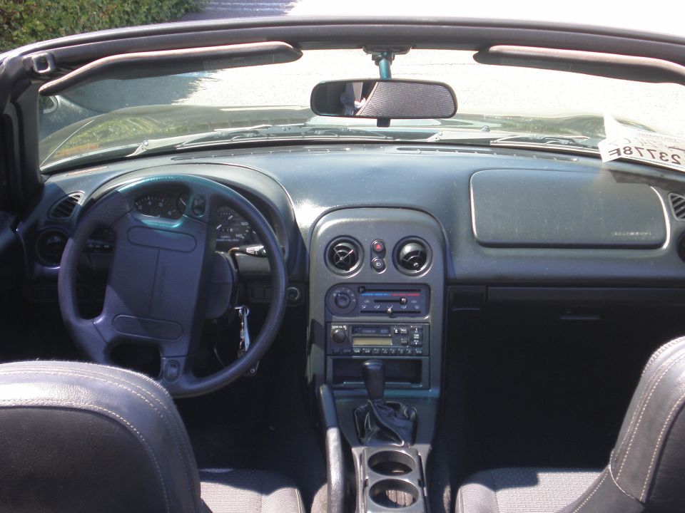 Interior of a 1996 Mazda Miata showing the dashboard, steering wheel, center console, and seats