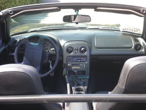 1996 Mazda Miata - The interior of a convertible sports car is visible, a steering wheel, dashboard, and center console.