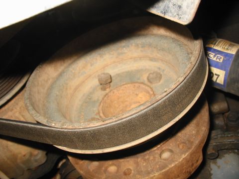 1988 Ford Bronco - Close-up view of a rusty engine pulley and belt, with a partial label in the background.