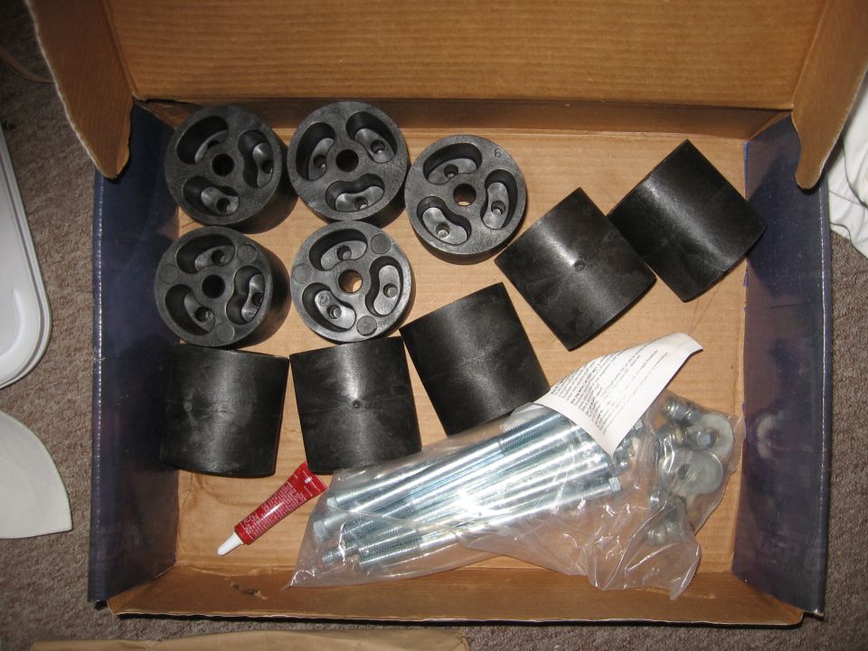 Body lift kit components including rubber pucks, cylinder spacers, bolts and hardware in cardboard box