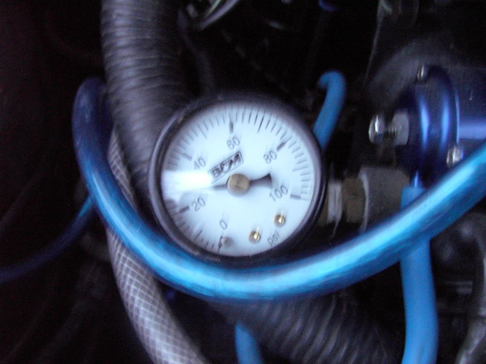 Close-up of a fuel pressure gauge with blue hoses