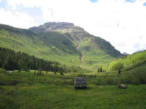 1986 Ford Bronco - A truck sits in a mountain meadow under a cloudy sky.