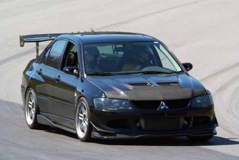 1995 Ford Probe - A black Mitsubishi Lancer Evolution with racing modifications is captured on a track.