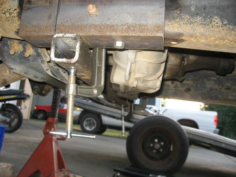 1990 Ford F-250 - Close-up view of a vehicle's undercarriage, showing transmission and suspension components, with a Supermotors logo at the bottom right.