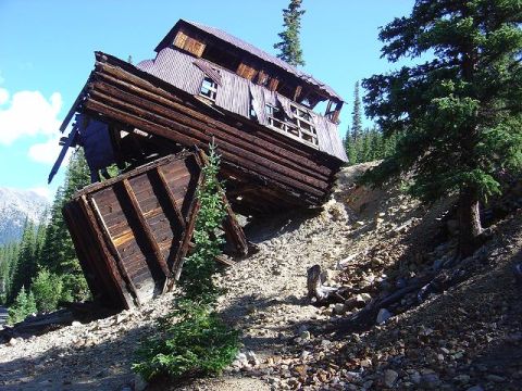 1986 Ford Bronco II - An old wooden structure collapses on a mountainside, surrounded by trees and debris.