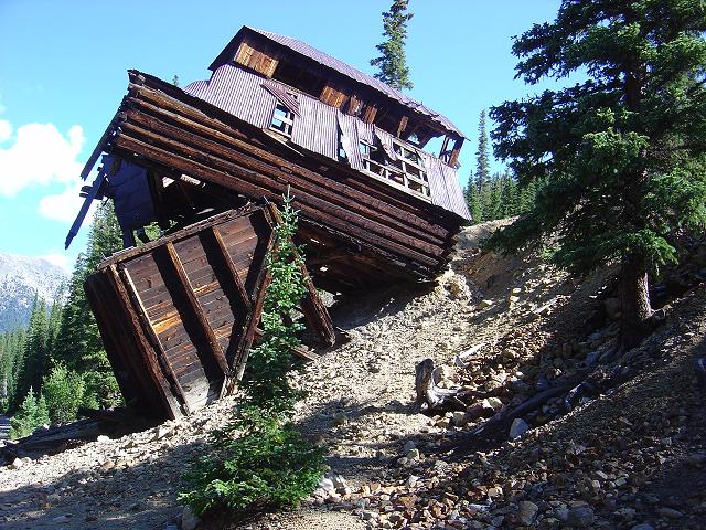 Dilapidated wooden building on a rocky slope under a blue sky