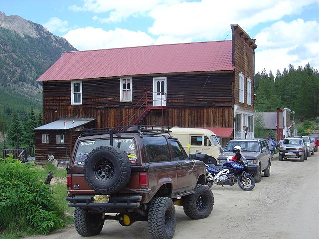 Brown Ford Bronco II with a spare tire on the back, lifted suspension, and roof rack