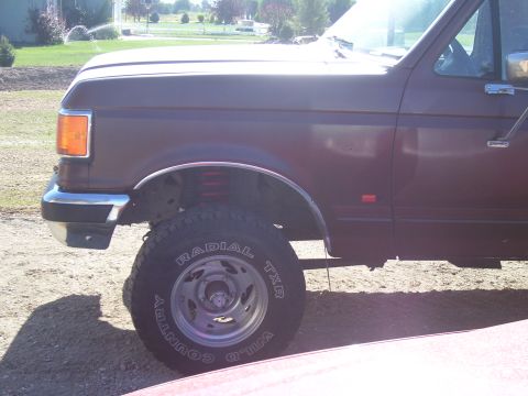 1990 Ford Bronco - This maroon Ford F-Series truck displays a lifted suspension and off-road tires, suggesting a model year around 1992.