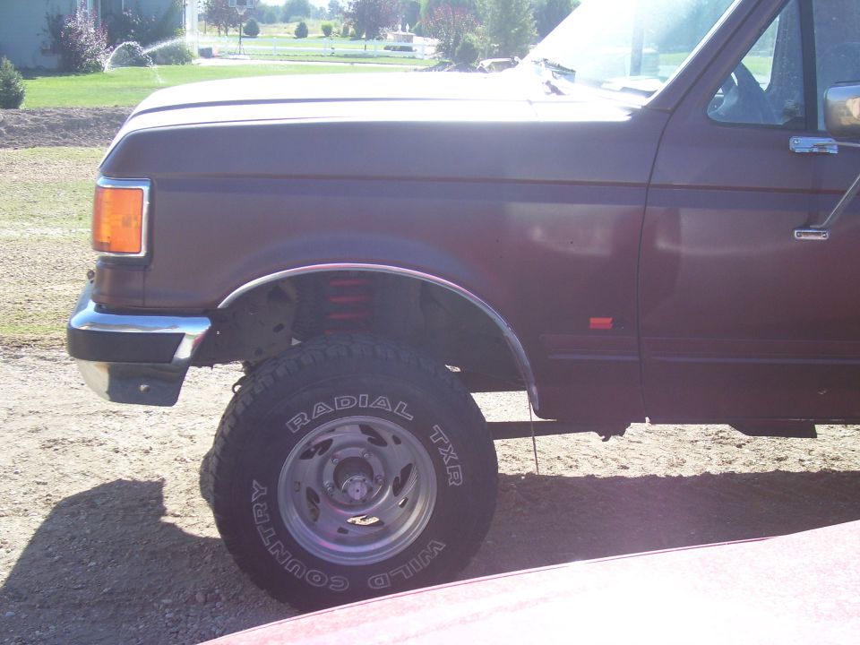 Maroon Ford F-Series truck, front quarter view, lifted suspension, off-road tires