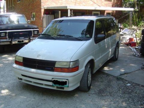 1979 Ford Bronco - A white minivan is parked in a driveway next to a black truck.