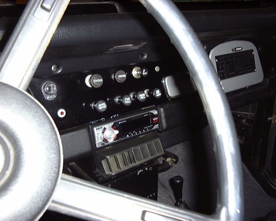 Dashboard with steering wheel, radio, and various switches. A plaque reads 'Land Cruiser'