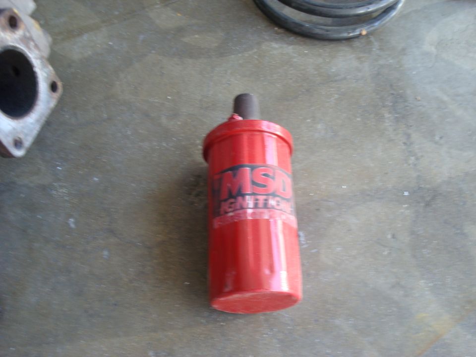 Red MSD ignition coil canister lying on a concrete floor